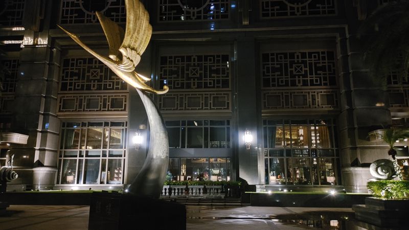 outside the first floor of the tower. And art deco latice work covers the front of the building with the statue just left of center in the image, also in art deco style