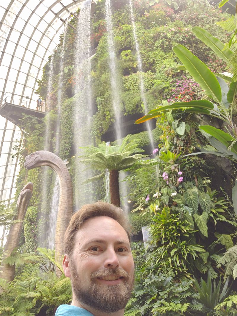 photo of me with waterfal dome behind me and brachiosaurus dinosaurs