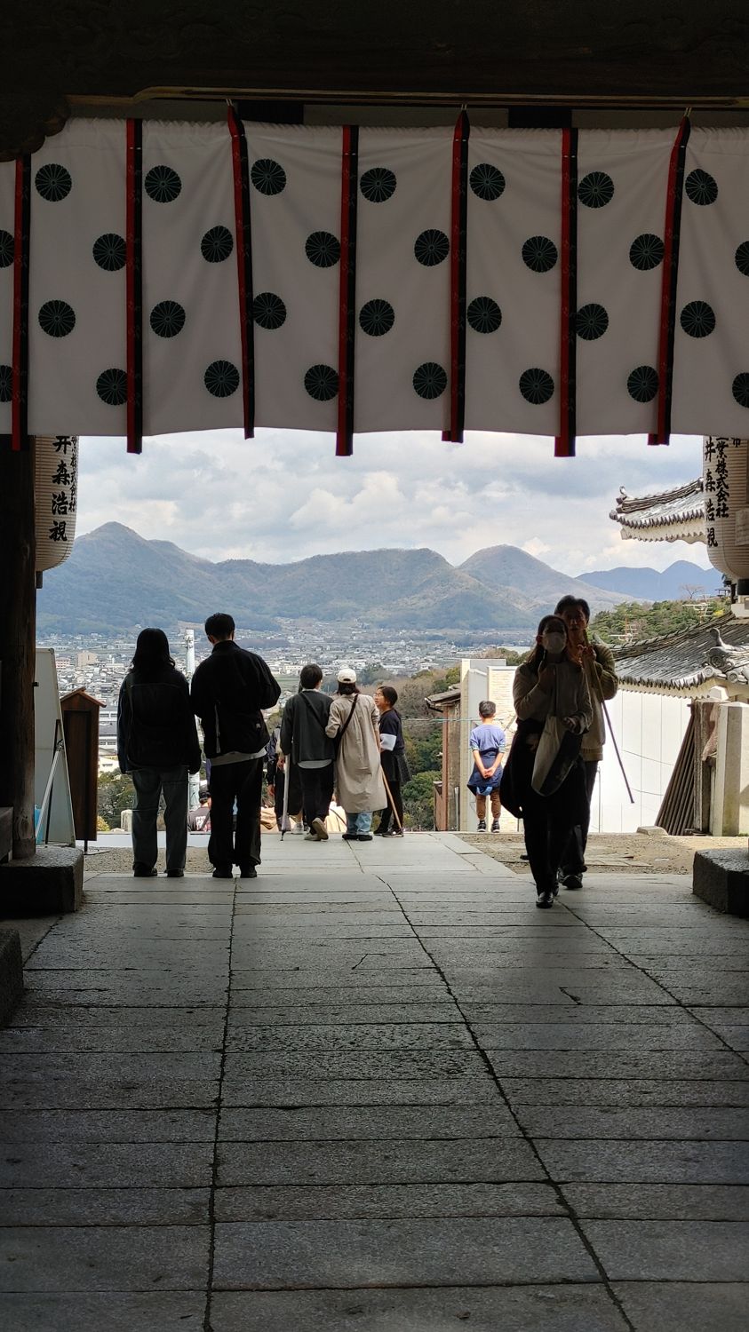 view overlooking the valley with mountains in the background. The view is through the wooden front gate building with a white banner above the mountain view