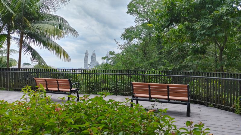benches with iron fence overlooking the distance with curved building spires in the distance that look like an evil building
