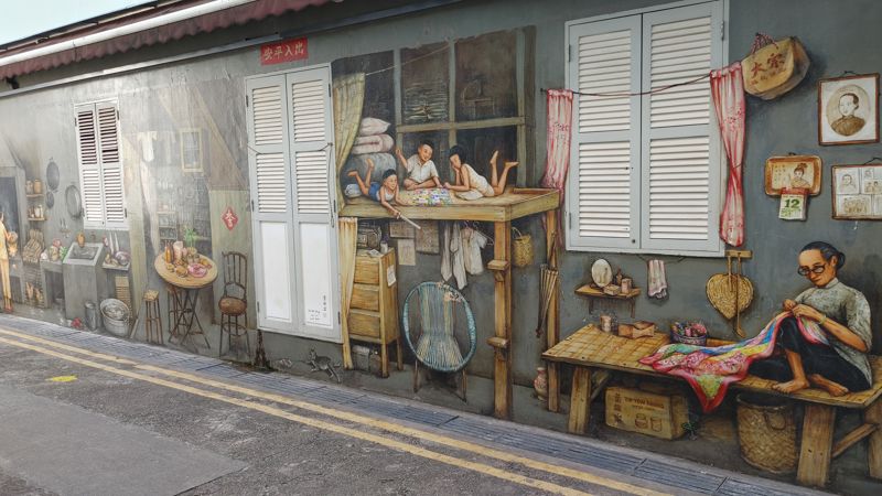mural depicting family life with children on a table, a women sewing, and others on the far left doing daily work