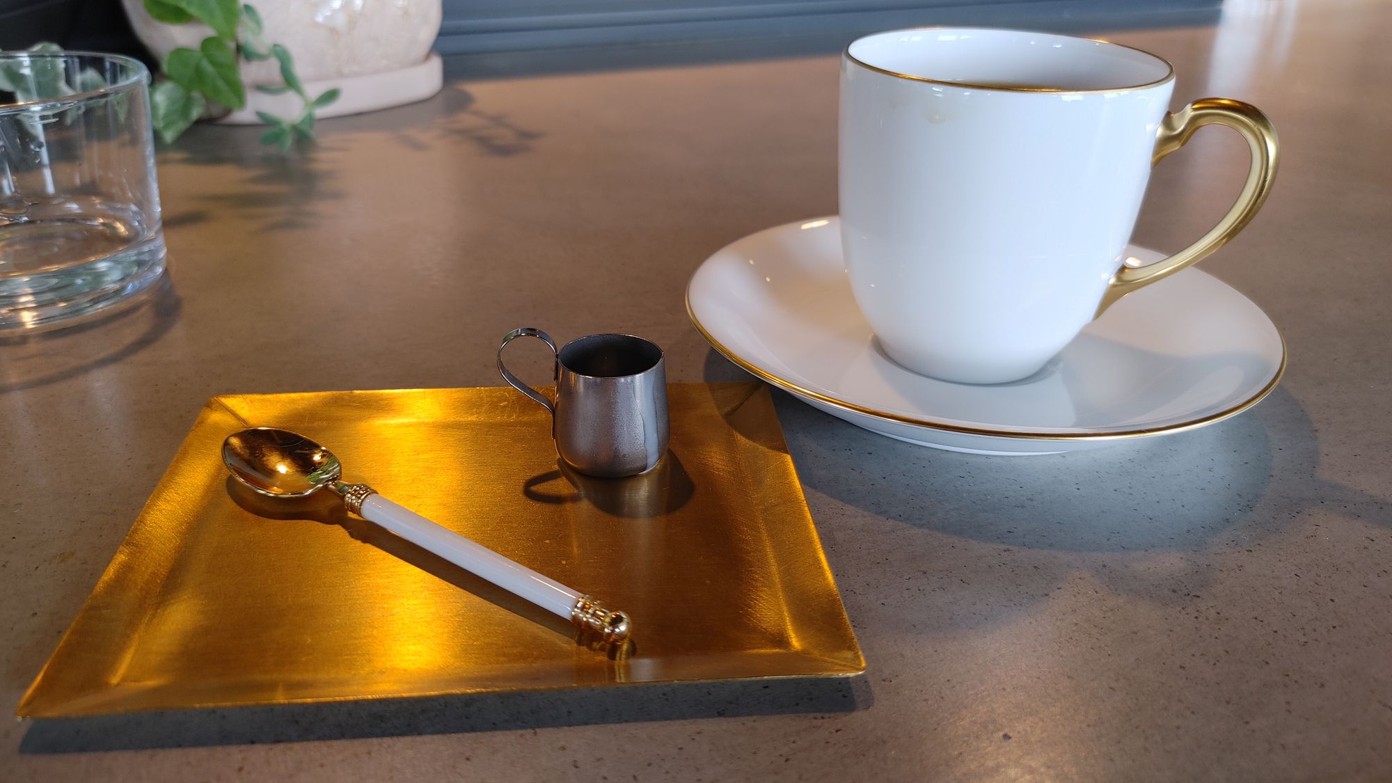 small coffee set with tiny milk cup on brass painting plate and stirring spoon